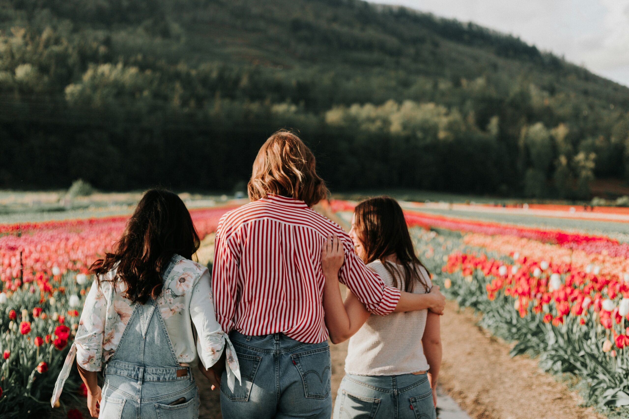 Mother walking through field of tulips with two girl children