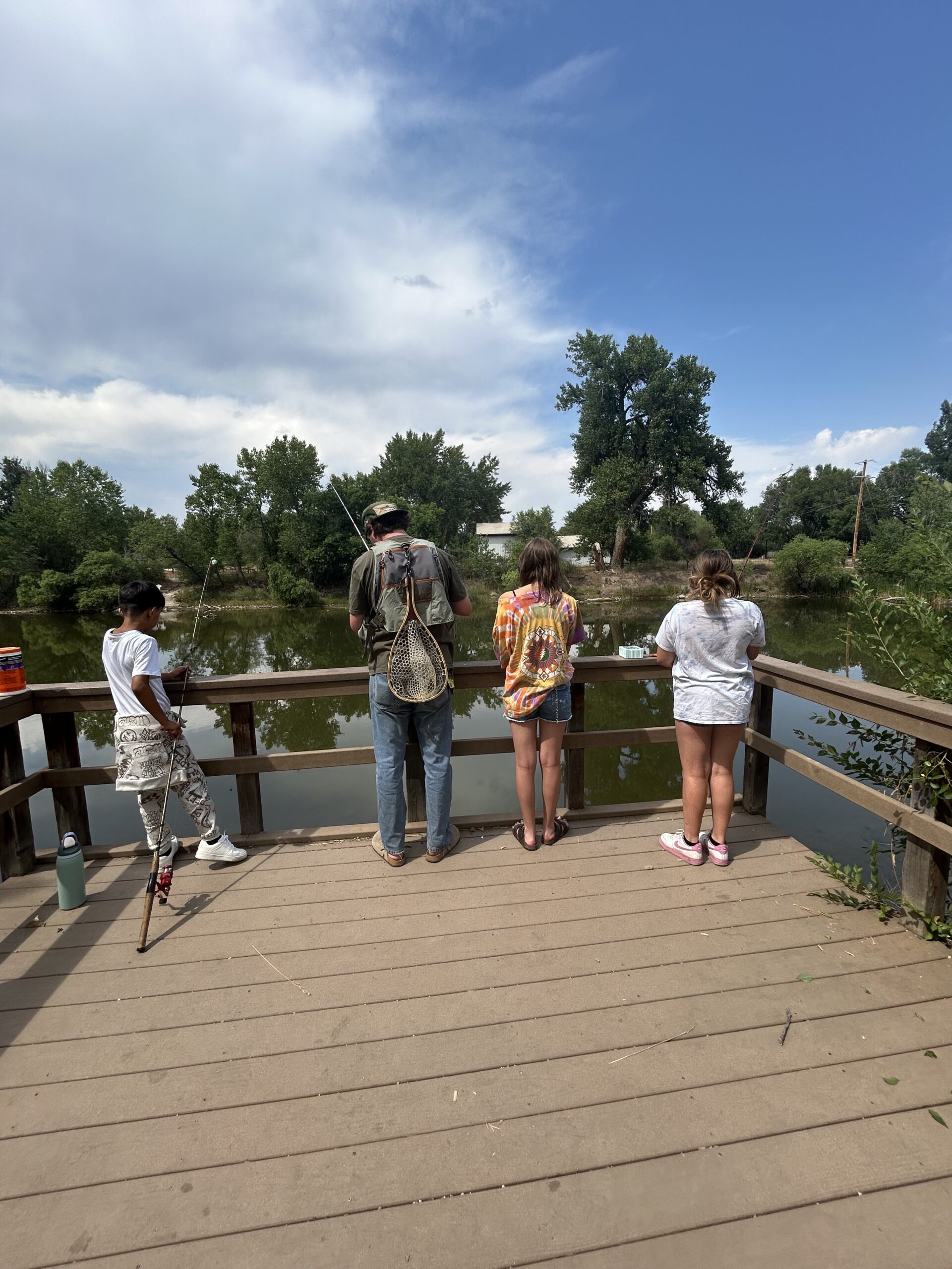 Youth and Family Engagement Worker with three youth on a dock fishing
